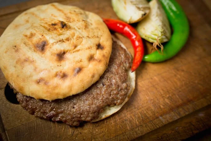 Pleskavica : steak haché grillé en pain plat, chou blanc et piments